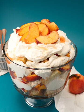 Trifle bowl layered with macerated peaches, pound cake and whipped cream.