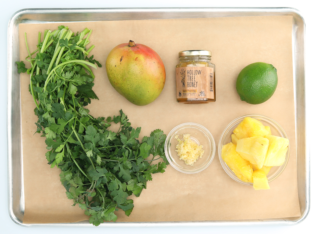 Ingredients needed to prepare fresh pineapple mango salsa laid out on a baking tray. 