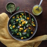 Top view of the kale mango chopped salad with the dressing in a small glass bowl and small dish of pepitas next to it.