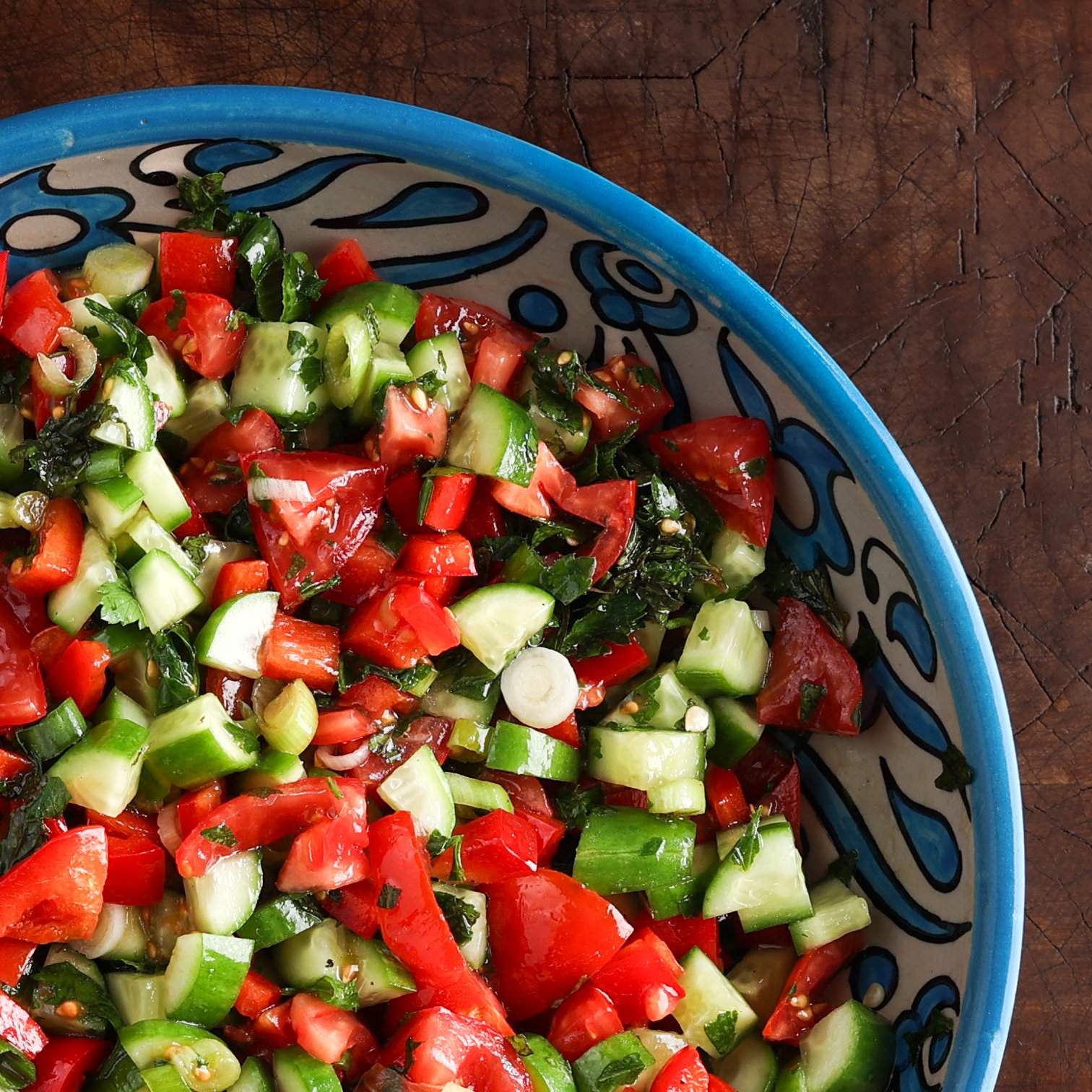 Close up of a Israeli cucumber tomato salad in a blue and white serving bowl.