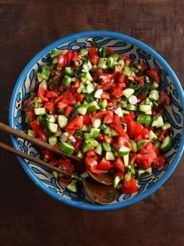 Beautifully painted serving bowl with a Jerusalem salad with tomatoes and cucumbers served in it.