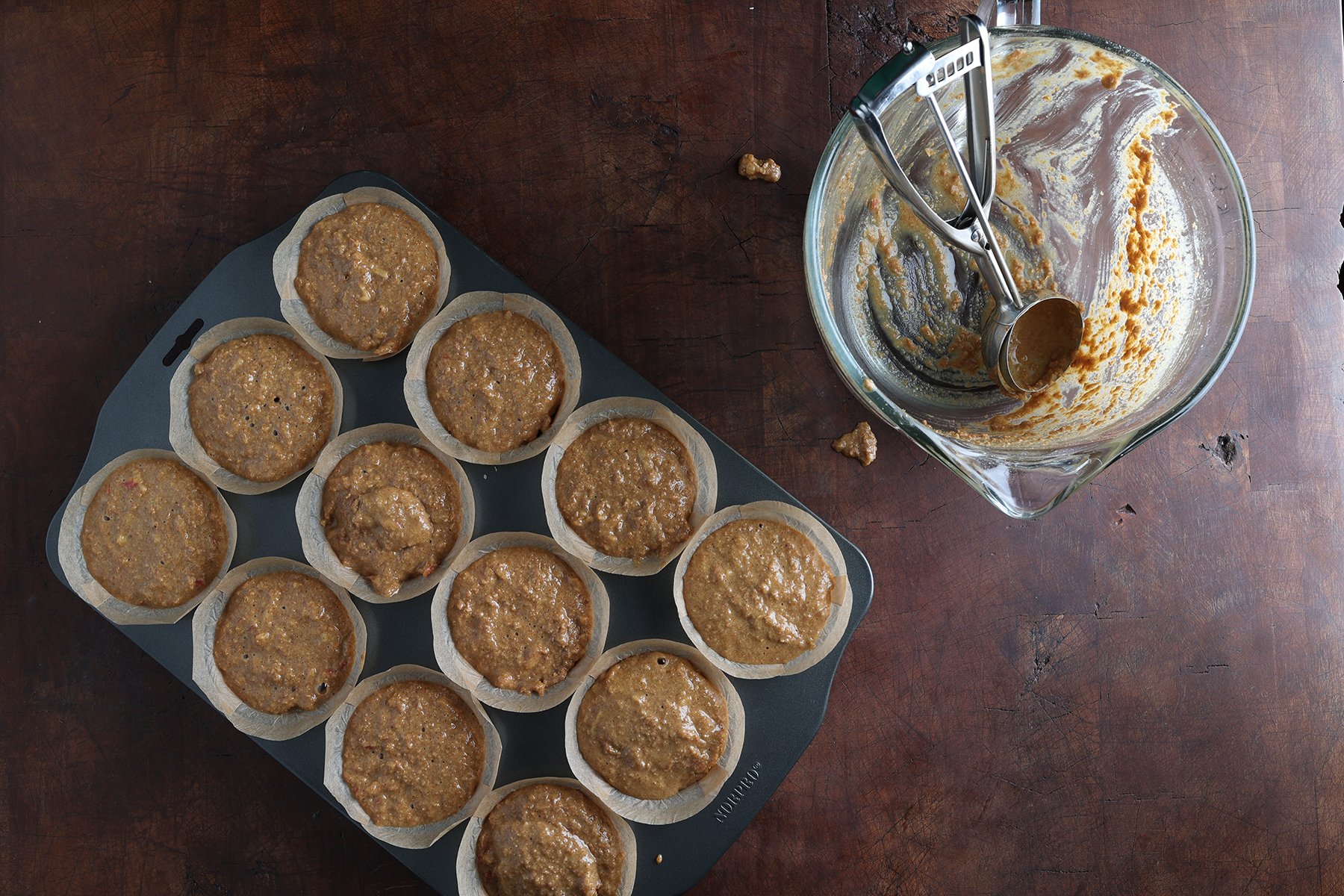 Muffin batter added to baking paper in a muffin tin, ready to bake.