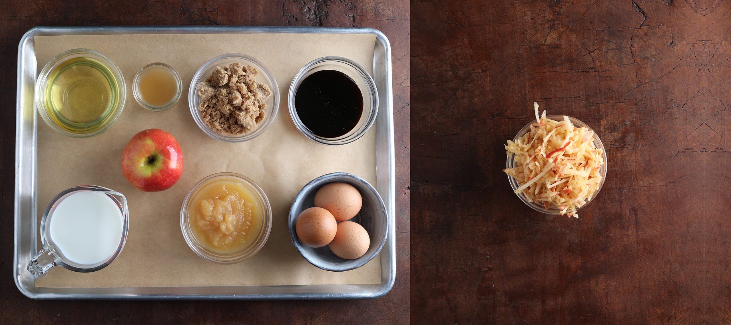 Ingredients laid out and measured on a baking sheet are used to prepare apple bran muffins with a second photo showing grated apples in a bowl.