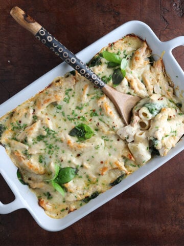Wooden spoon resting in a rectangular baking dish with a scoop ready to serve.