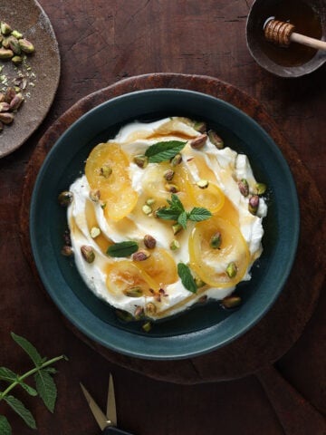 Labneh cheese on a plate topped with pistachio nuts and glaceed lemons.