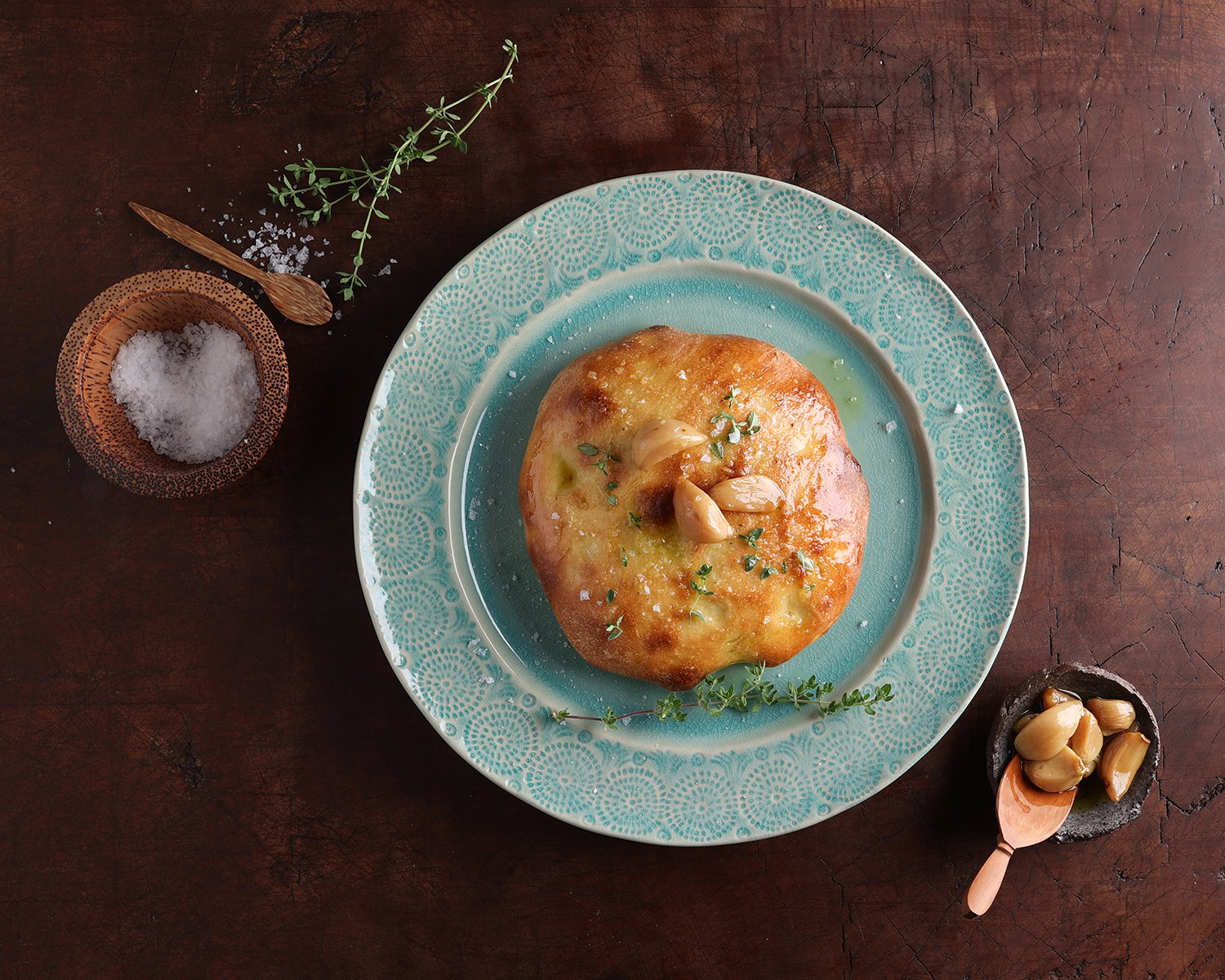 Frena Moroccan bread served on a plate with a small dish of garlic resting next to it.