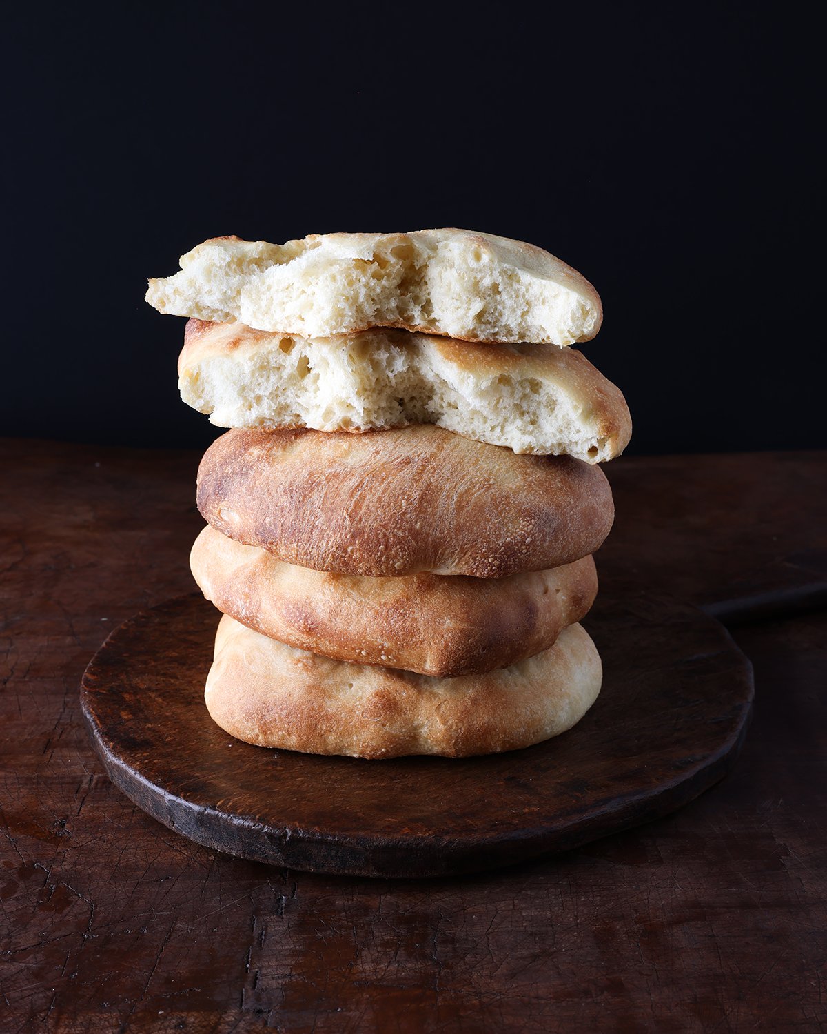 Stack of 5 homemade Moroccan bread called Frena with a bite taken out of one.