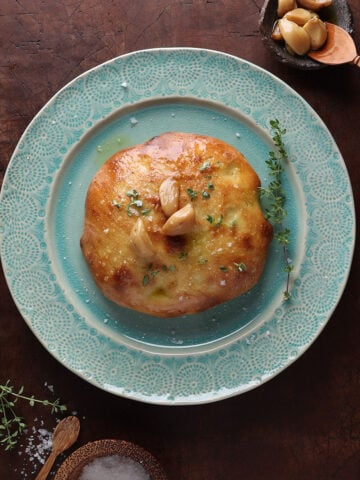 Frena topped with roasted garlic laid out on a plate.