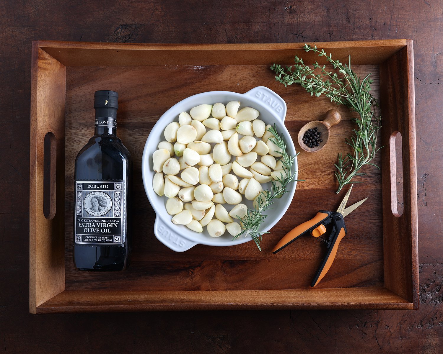 Ingredients laid out on a wooden tray to prepare garlic confit.
