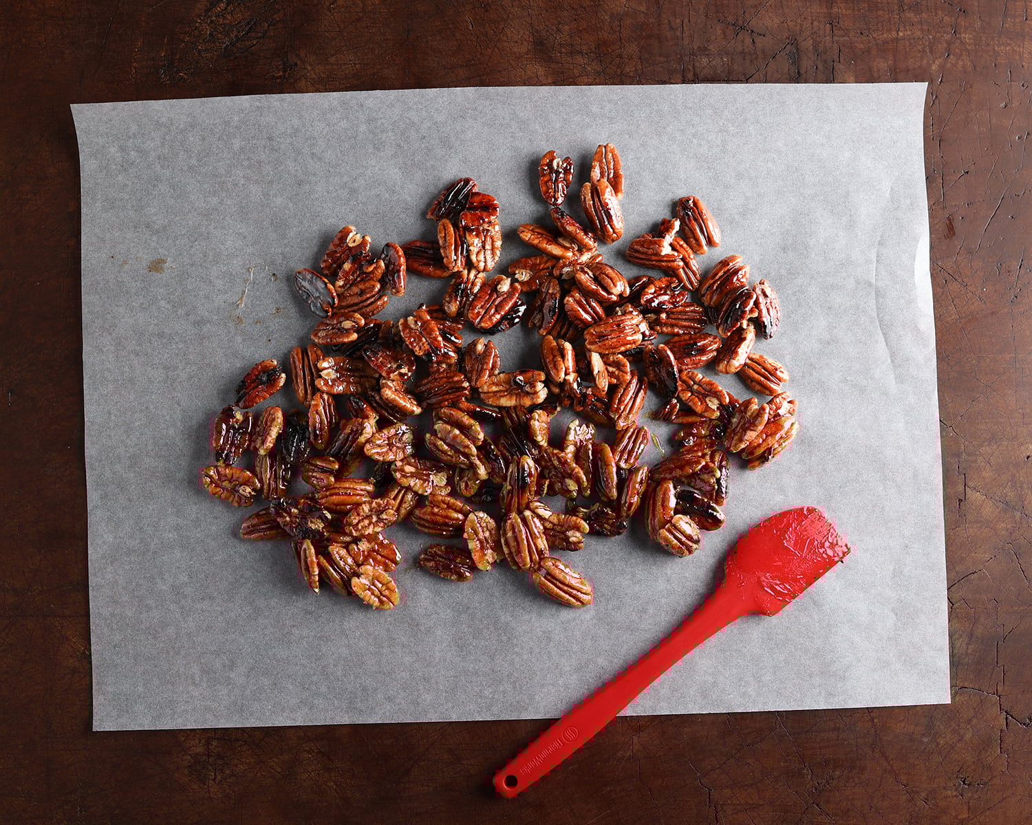 Close up of maple glazed pecans cooling on parchment paper.