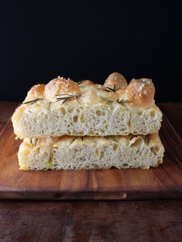 Fresh focaccia loaf cut in half and stacked on each other.