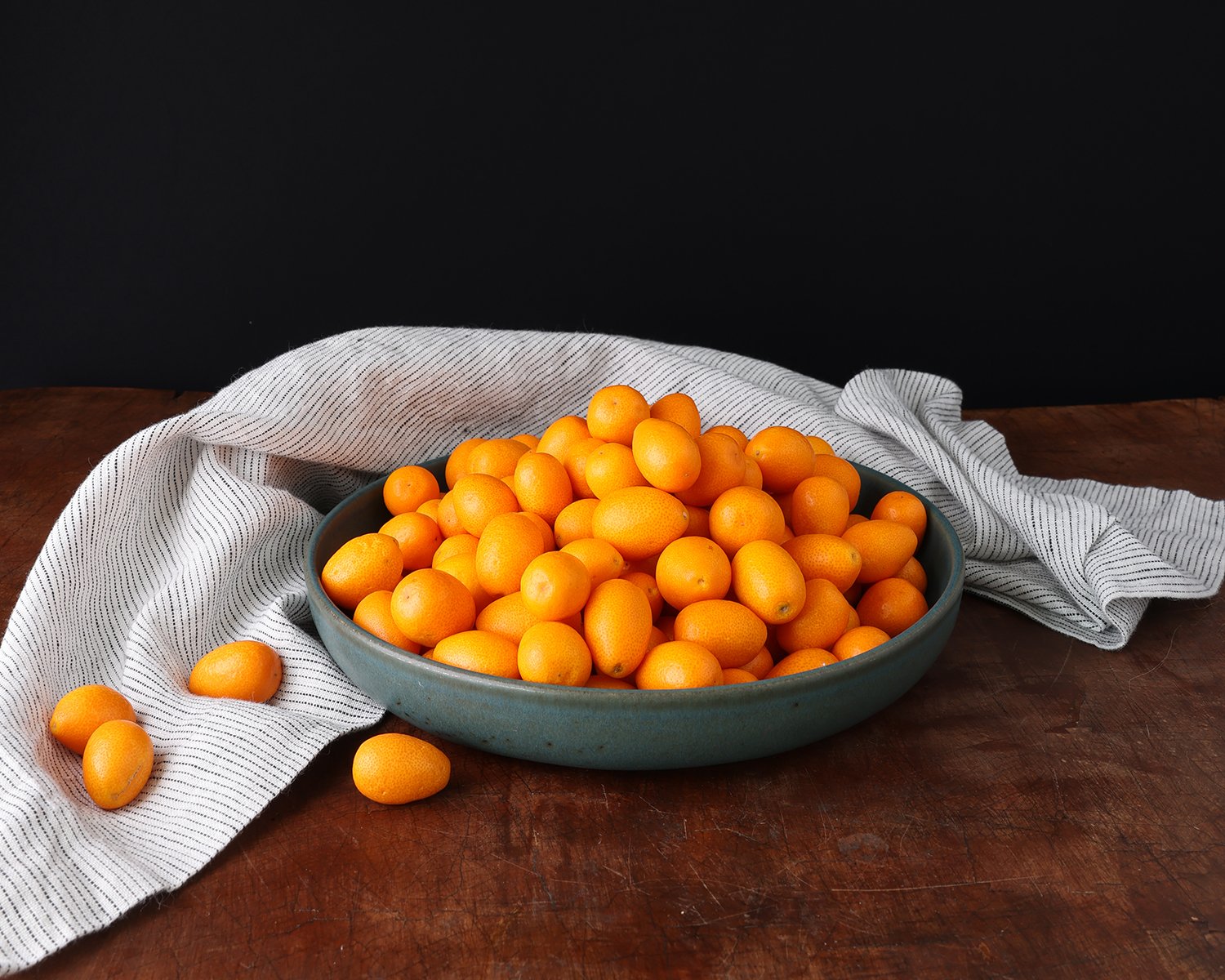 Overflowing bowl of bright orange kumquats.