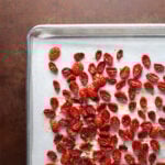 Roasted cherry tomatoes that have become sun-dried tomatoes on a baking sheet.