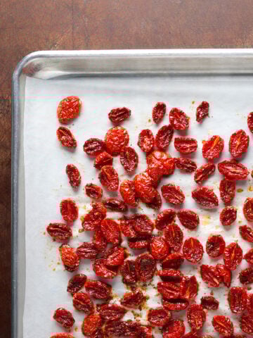 Roasted cherry tomatoes that have become sun-dried tomatoes on a baking sheet.