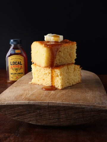 Honey oozing off the top of two pieces of sweet cornbread stacked together.