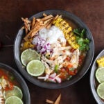Bowl of chicken and rice lime soup garnished with lime rounds.