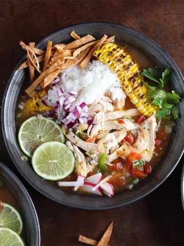 Bowl of chicken and rice lime soup garnished with lime rounds.