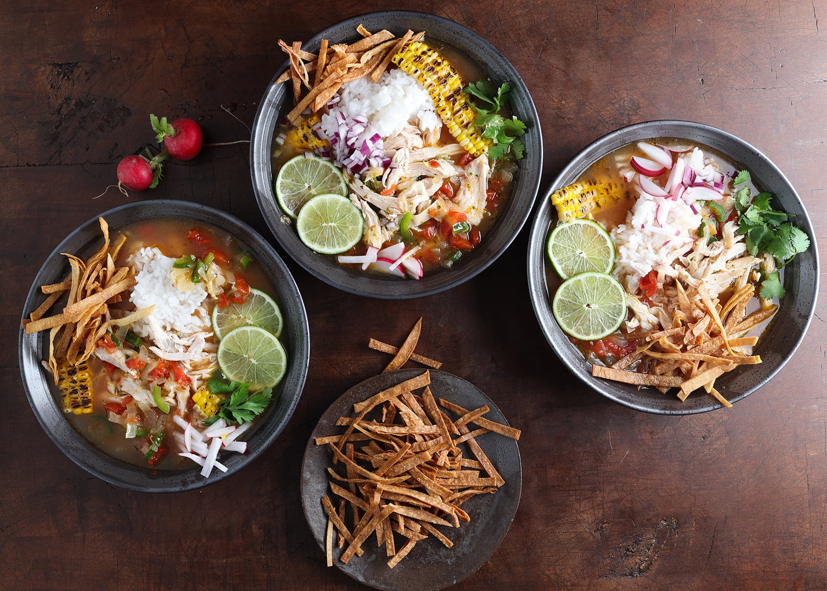 Overhead views of southwest lime chicken and rice soup with a small dish of tortilla strips to use for garnishing.