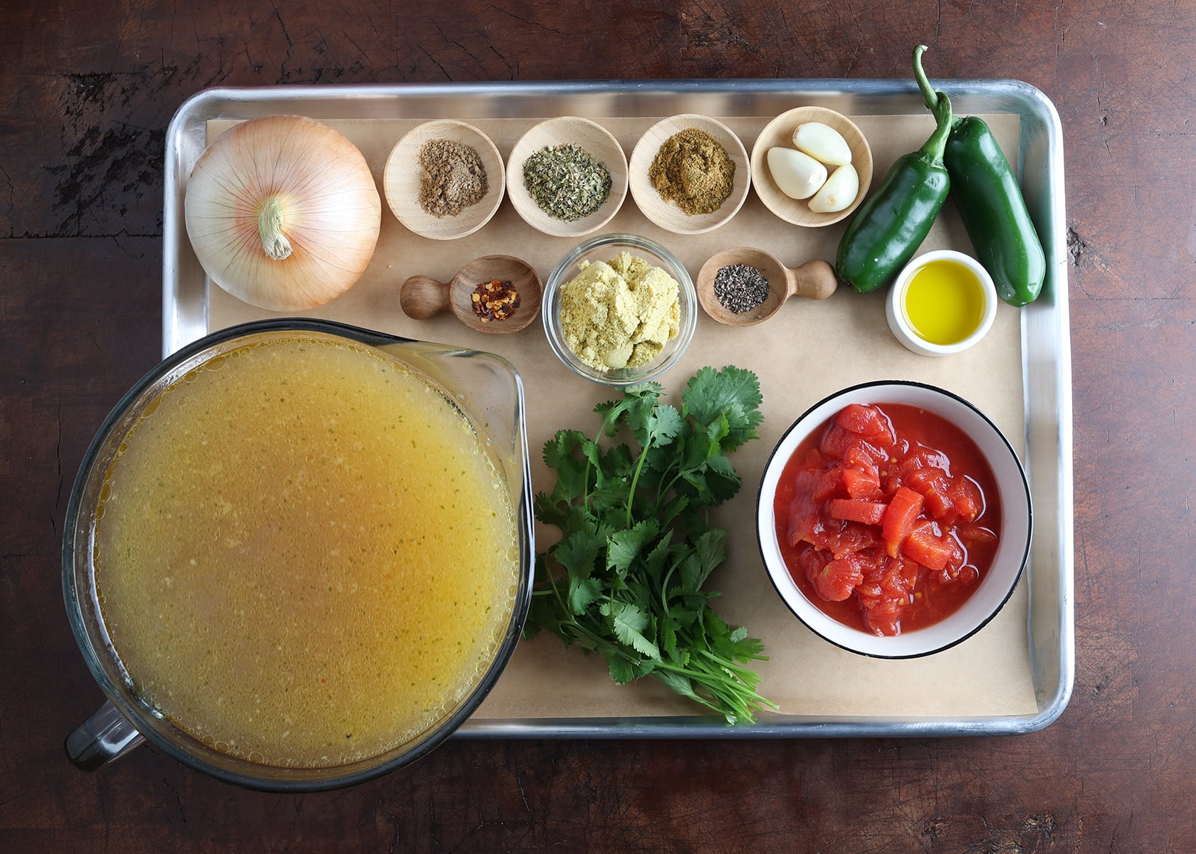Spices and fresh ingredients measured out that are used to flavor a southwest soup with chicken and rice.