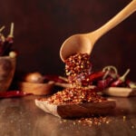 chili flakes poured into a wooden dish on a nice wooden background