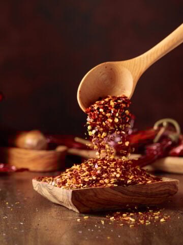 chili flakes poured into a wooden dish on a nice wooden background