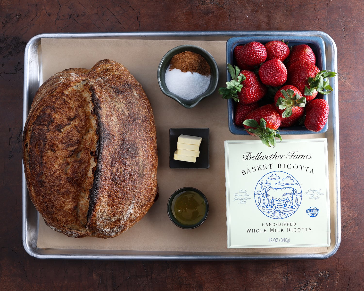Ingredients laid out on a baking tray that make up strawberry ricotta toast recipe.
