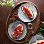 Strawberry ricotta toast served on plates on a wooden tray.