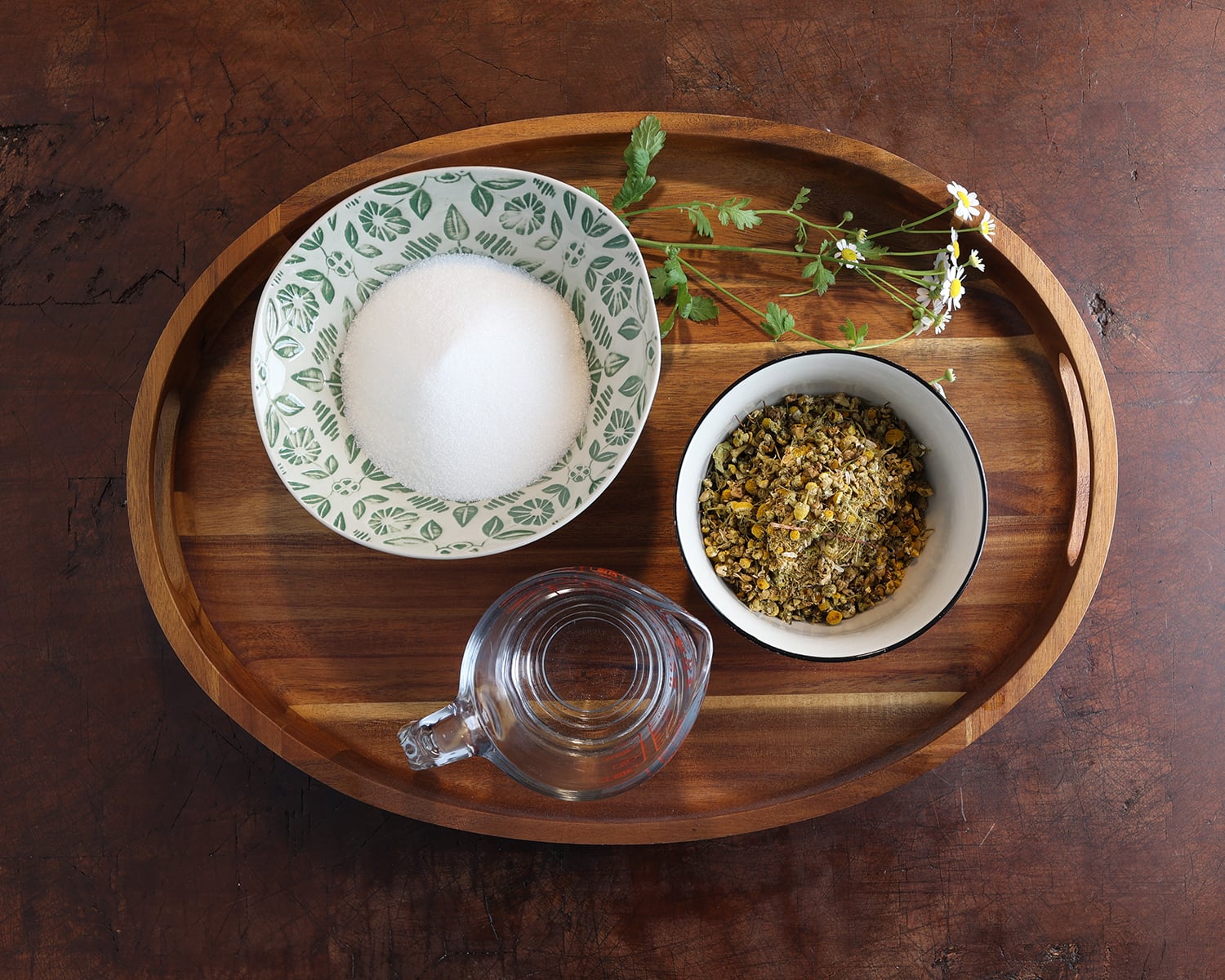 Sugar, chamomile dried flowers and water measured out in containers.