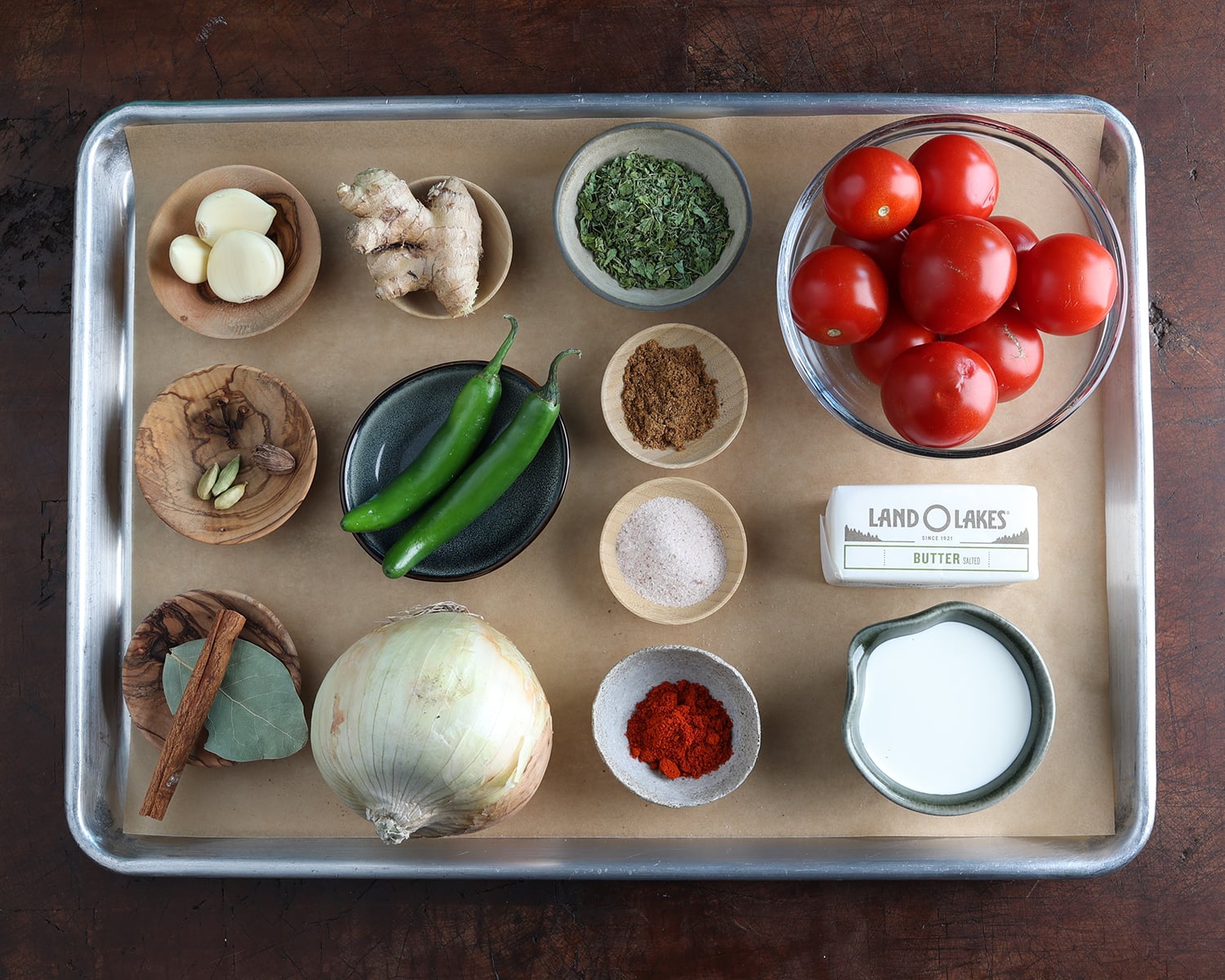 Ingredients maid out on a baking sheet that are used to prepare Dal Makhani.