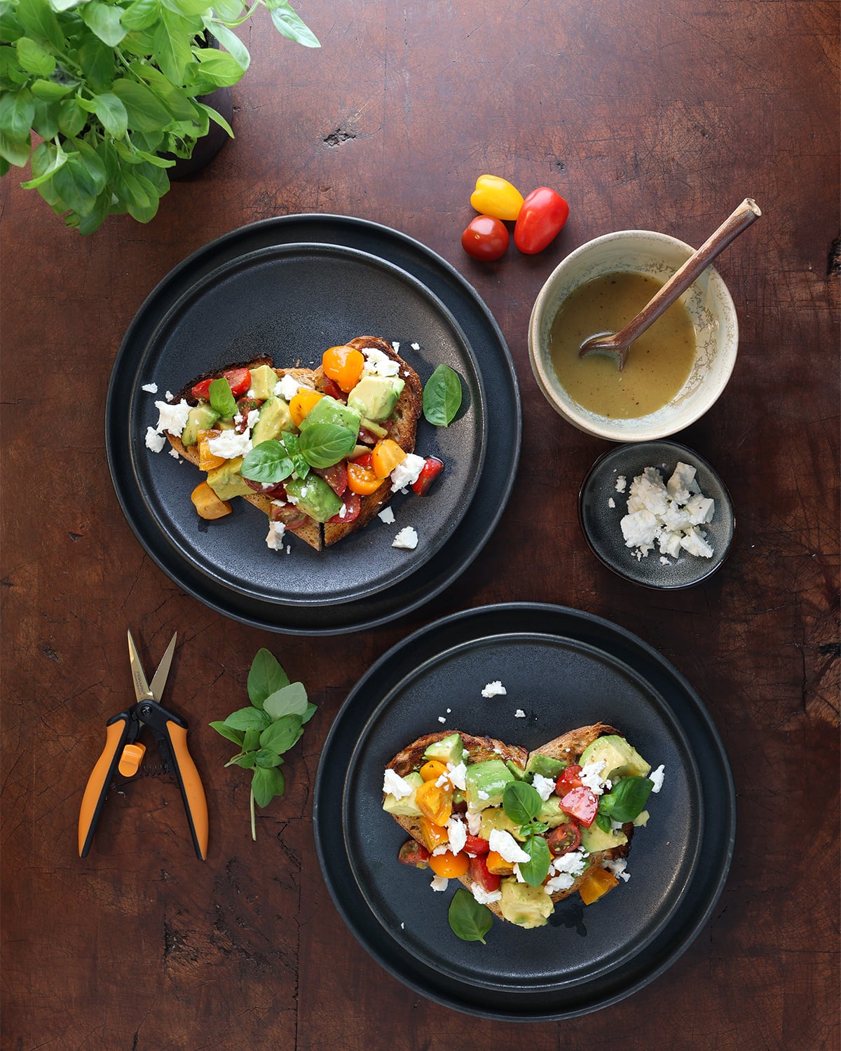 Honeymoon avocado toast served on plates with fresh herbs laying on the side.