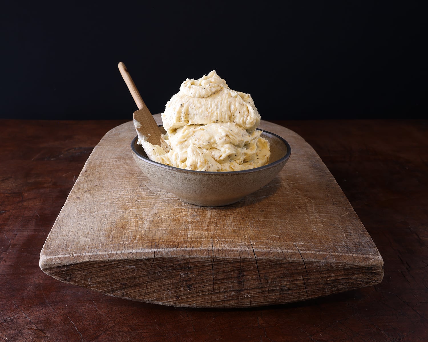 Whipped garlic confit butter served in a bowl with a wooden serving spoon.