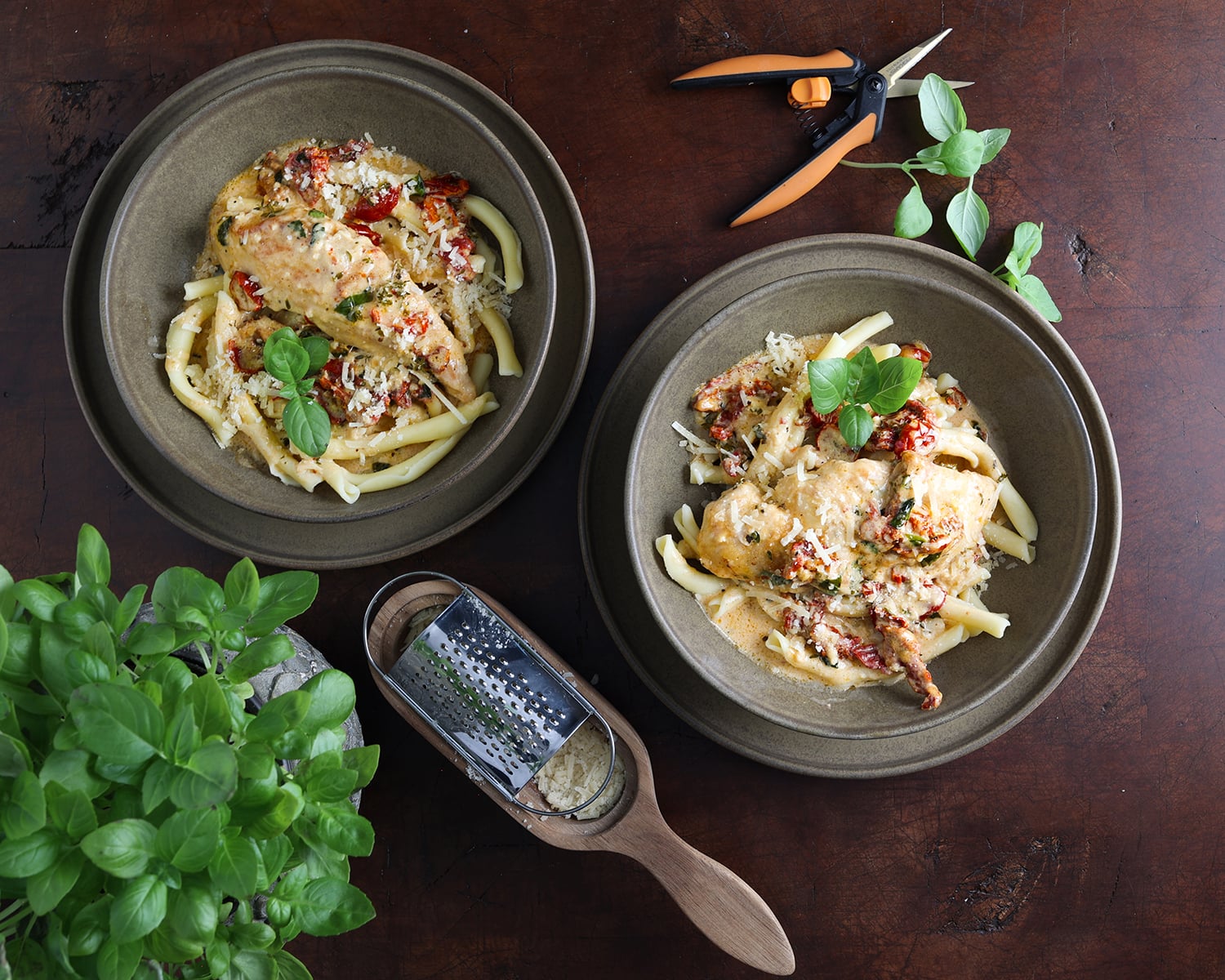 Shaved parmesan garnished over Marry Me Chicken in bowls with fresh basil on the side.
