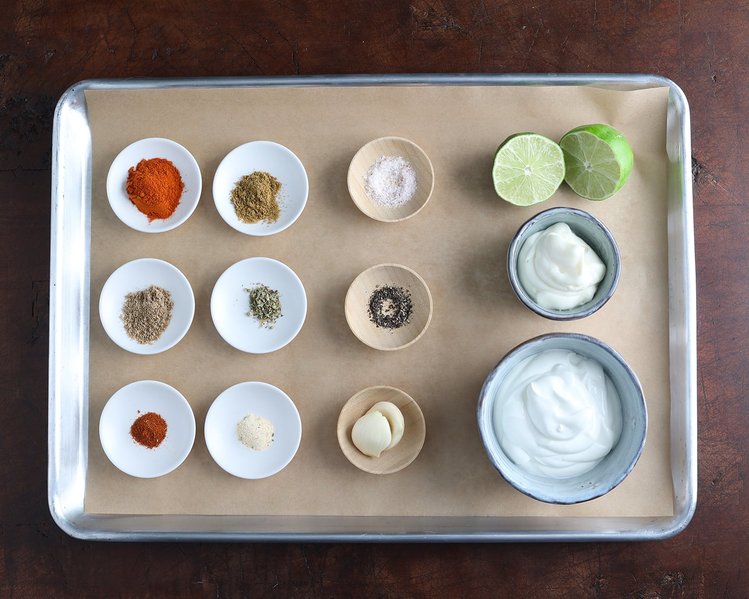 Seasonings and sauce ingredients measured out and laid out on a baking sheet.