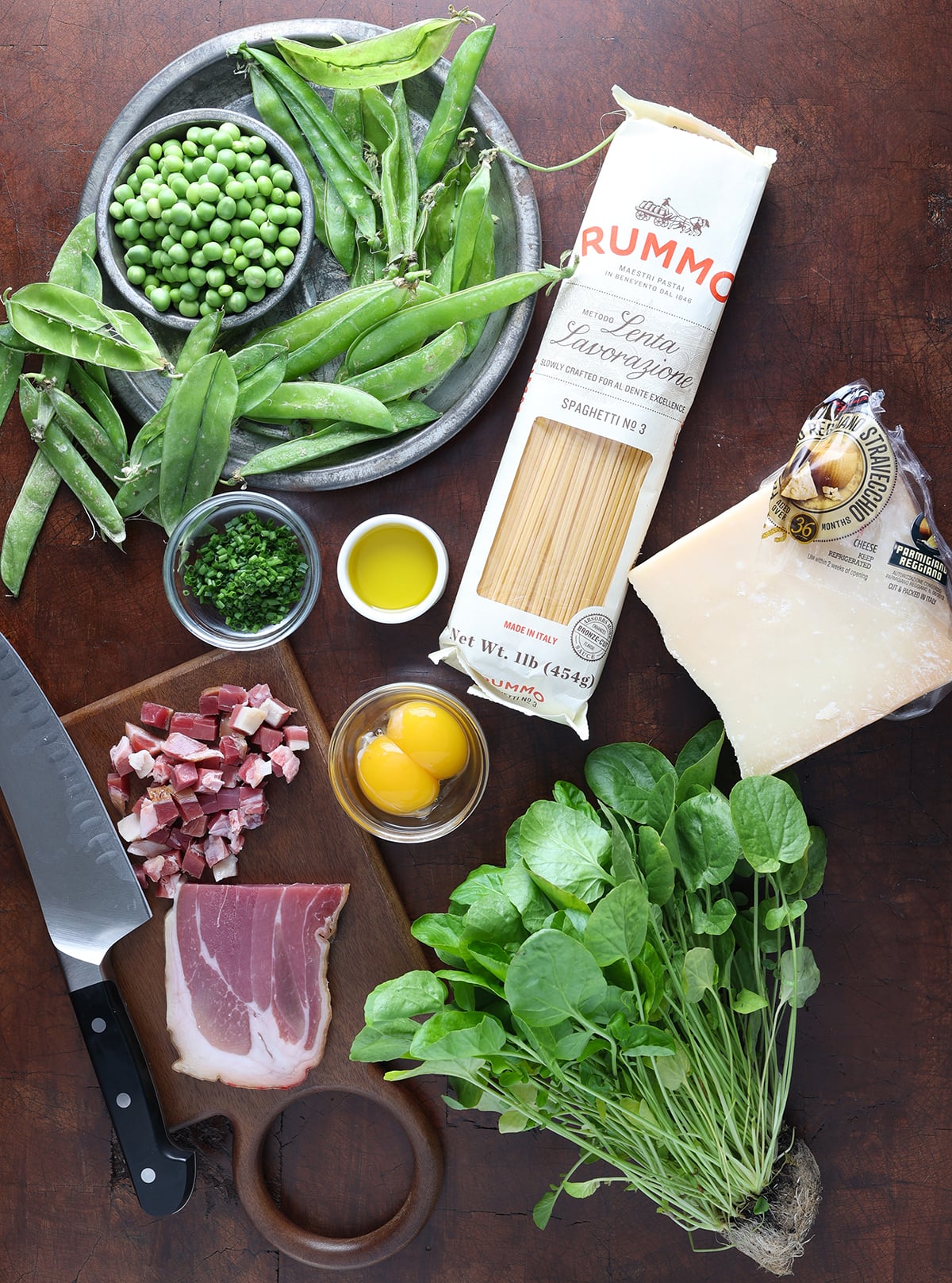 Ingredients laid out to show what's used to prepare carbonara with english peas.