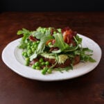 English peas served over a piece of toast lathered in herbed goat cheese and topped with crispy bacon pieces and arugula.
