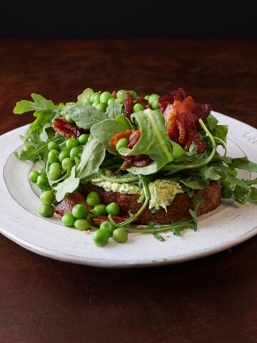 English peas served over a piece of toast lathered in herbed goat cheese and topped with crispy bacon pieces and arugula.