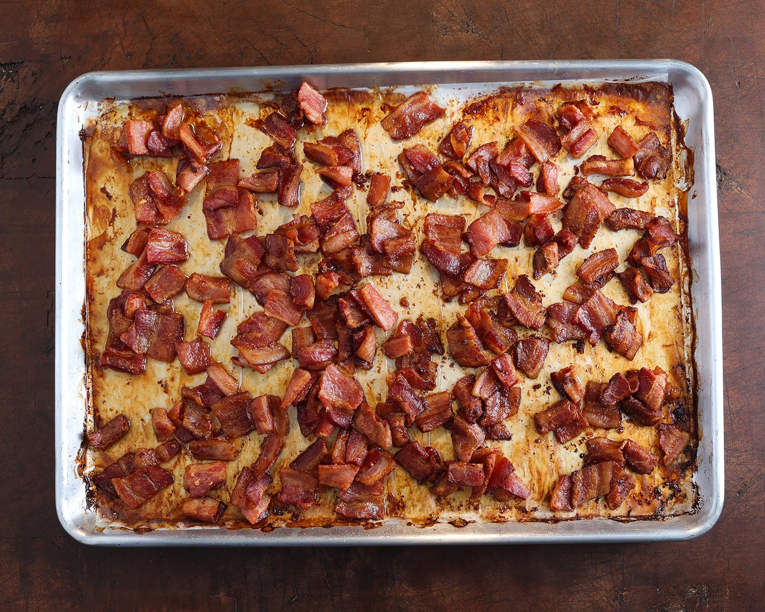 Close up of crispy bacon pieces on a baking sheet.