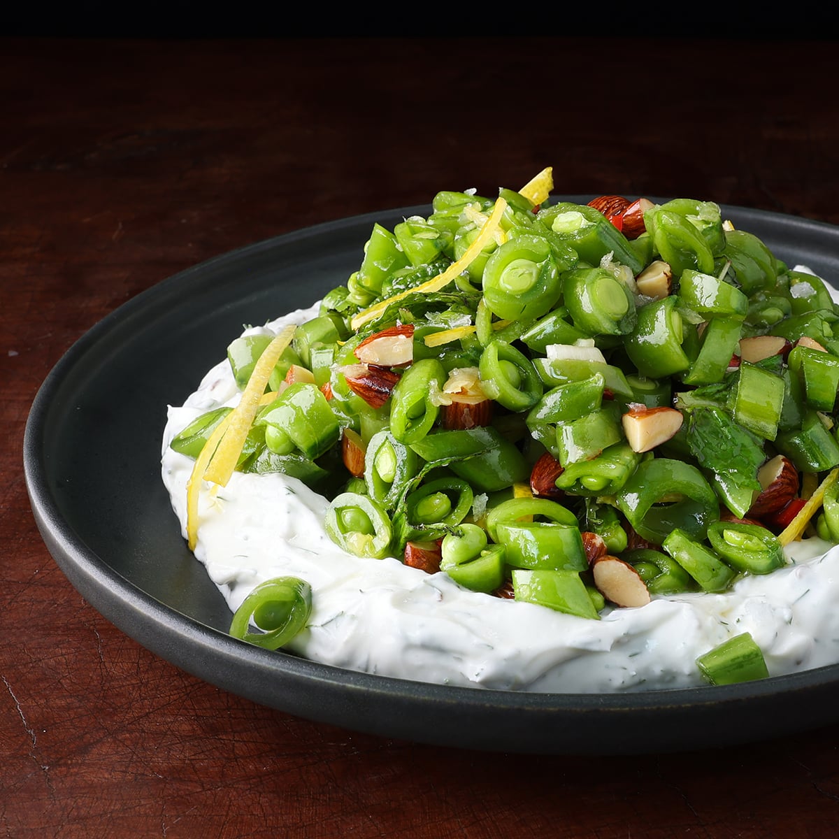 Spring sugar snap pea salad with greek yogurt served on a black plate