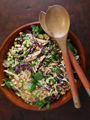Top view of a Vietnamese chicken vermicelli salad with fresh herbs in a large wooden bowl.