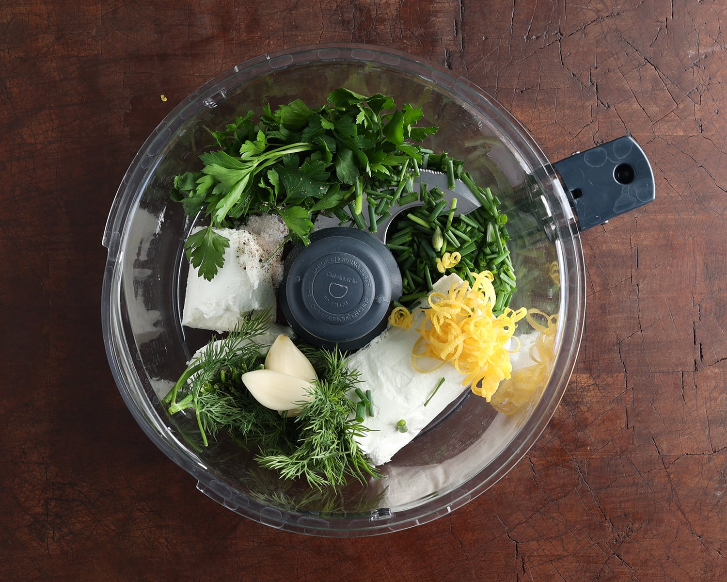 Ingredients to prepare herbed goat cheese added to a food processor before combining.
