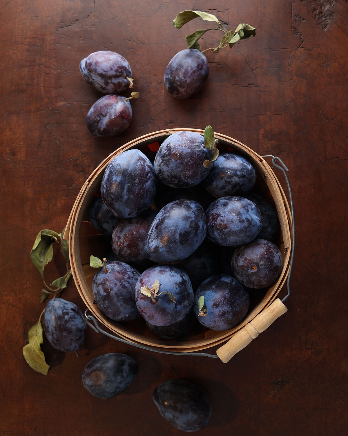 Basketful of empress plums with the leaves still attached.