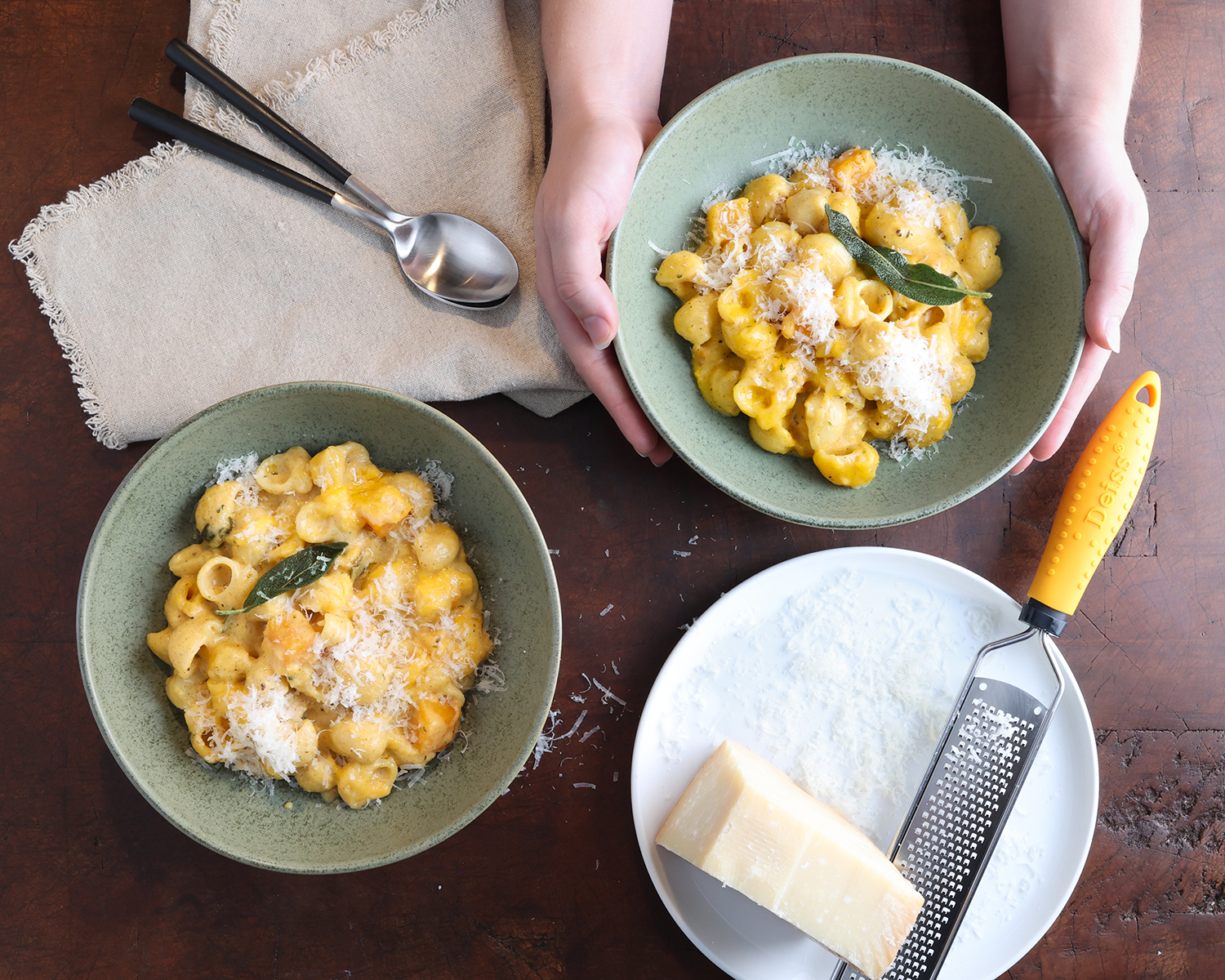 Top view of two bowls of butternut squash mac and cheese topped with fresh grated parmesan cheese.