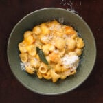 A sage leaf garnished over a bowl of butternut squash mac and cheese.